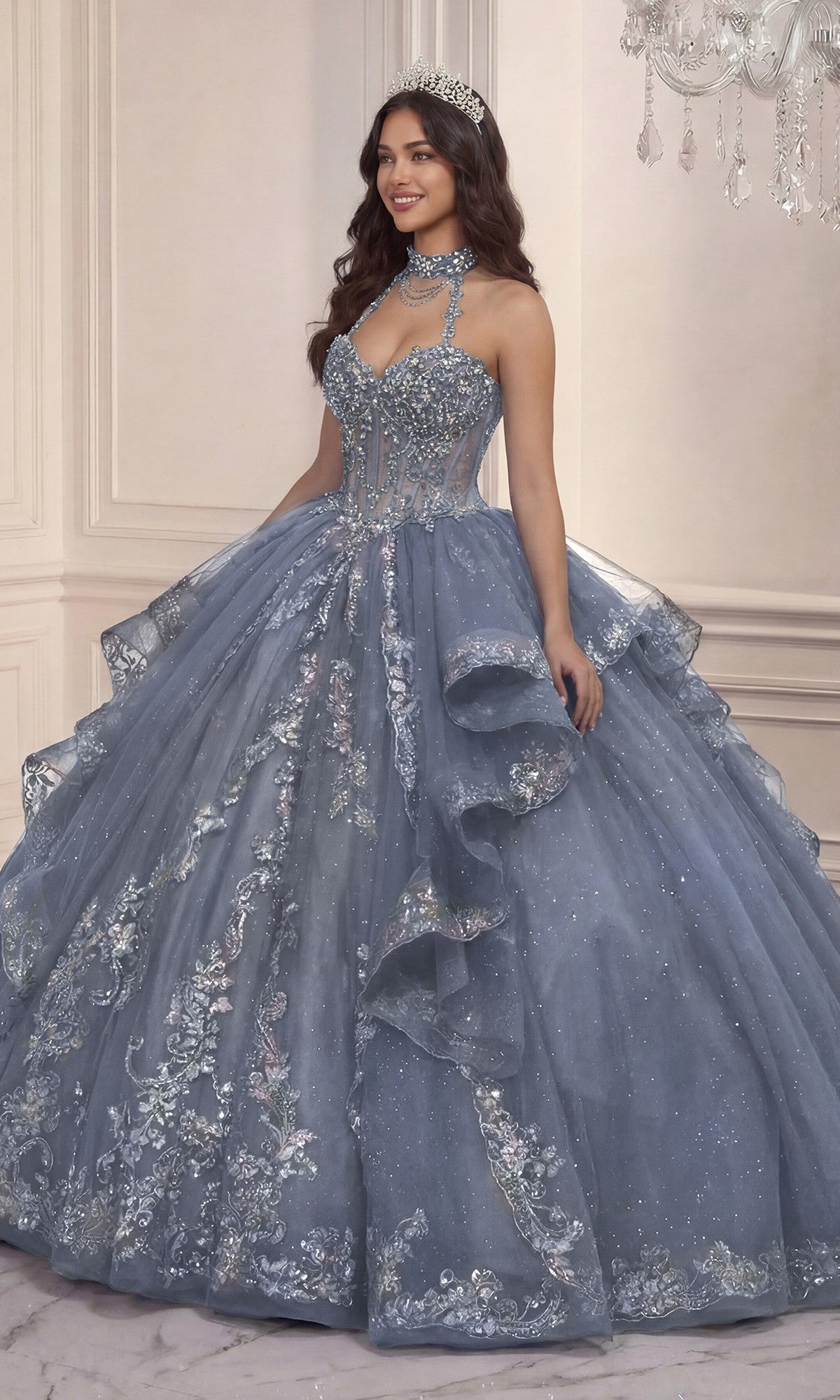 Indoors, a woman wears the Quinceanera Dress 15741 By Ladivine in dusty blue, featuring floral details, glitter tulle, and a matching tiara.